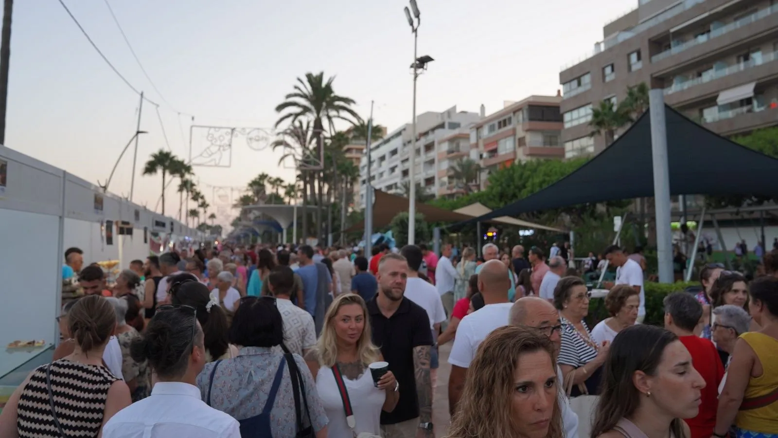 Público paseando entre los puestos al atardecer