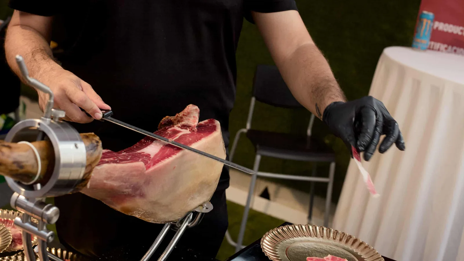 A carver in black gloves slices a ham, 2025