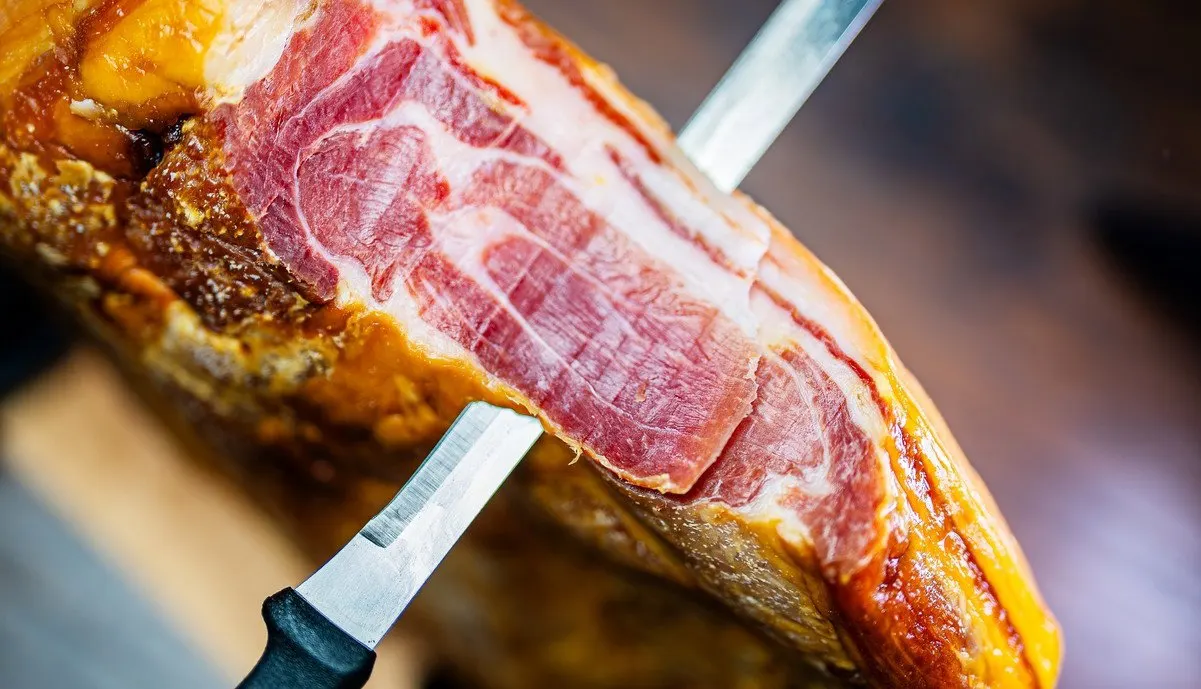A slice of ham on the blade of the knife